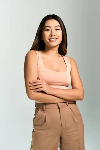 A woman with long dark hair smiles and stands with her arms crossed in front of her. — Stock Photo