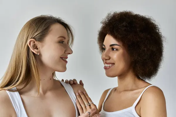 Due donne condividono uno sguardo amorevole, i loro sorrisi risplendono su uno sfondo bianco — Foto stock