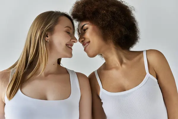 A close-up portrait of an interracial lesbian couple in white tank tops, their faces close together in a moment of intimacy. — Stock Photo