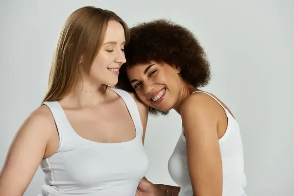 Two women in white tank tops smile and gaze affectionately at each other — Stock Photo