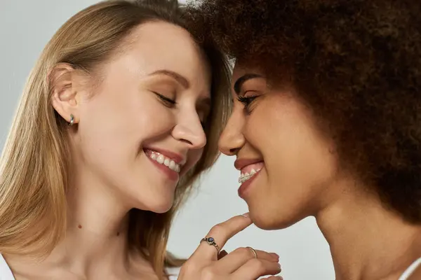 Two women, one with long blonde hair and the other with curls, share a tender moment, their smiles radiating love and affection. — Stock Photo