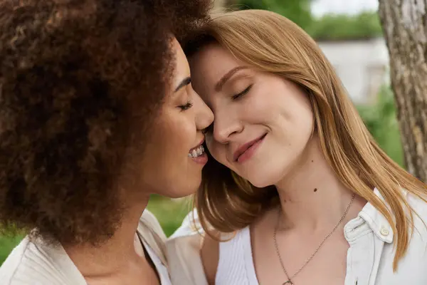 Una mujer negra y su pareja comparten un momento tierno, sus frentes se tocan, los ojos cerrados y sonríen en sus rostros. - foto de stock