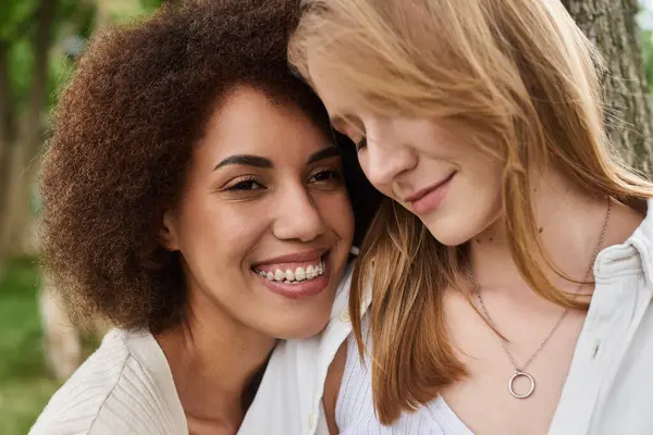 Two women, lesbian couple, smile at each other in a park. — Stock Photo