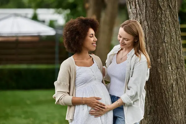 A pregnant Black woman and her partner stand together in a park — Stock Photo