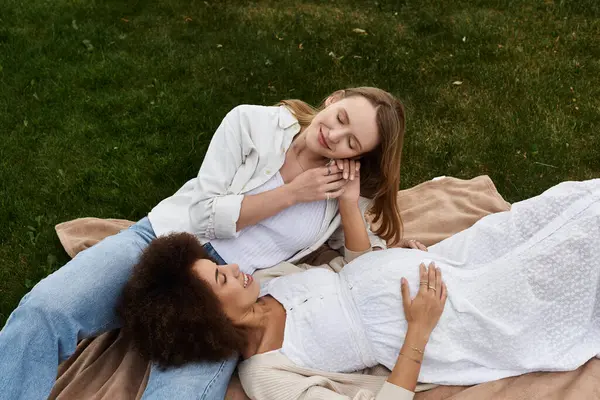 A pregnant woman rests her head on her partners lap while enjoying a sunny day outdoors. — Stock Photo