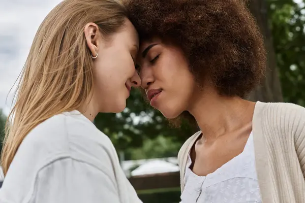 Zwei Frauen umarmen sich in einem zarten Moment, wobei sich ihre Stirn berührt, während sie im Freien sind. — Stockfoto