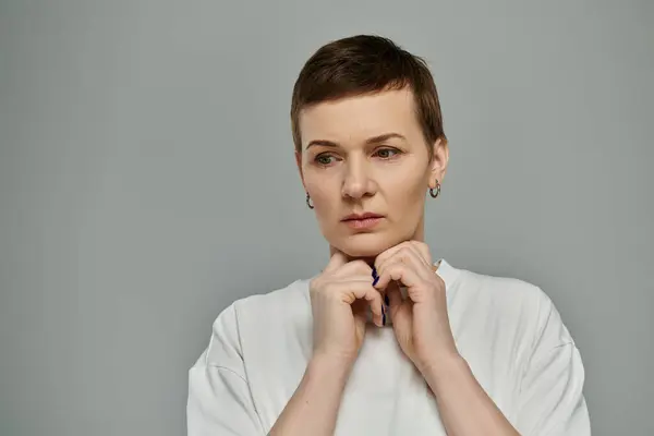 A woman in a white shirt with short brown hair, looking down with a serious expression — Stock Photo