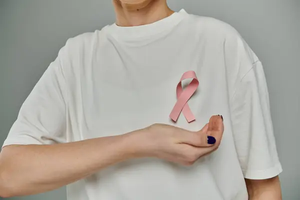 Una donna che indossa una t-shirt bianca con un nastro rosa attaccato al petto. — Foto stock