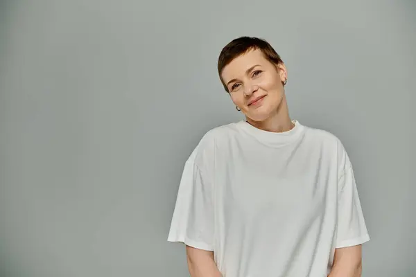 A woman with short hair wearing a white t-shirt, smiles subtly while facing the camera — Stock Photo