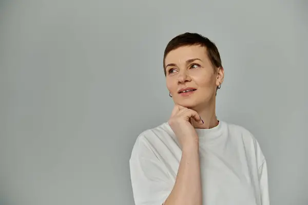 A woman with short hair wears a white t-shirt, thoughtfully gazing to the side. — Stock Photo