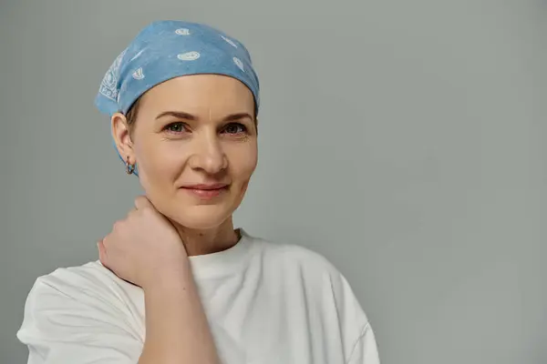 Женщина с короткими волосами носит синюю бандану и тихо улыбается, демонстрируя свою поддержку раку груди.. — стоковое фото