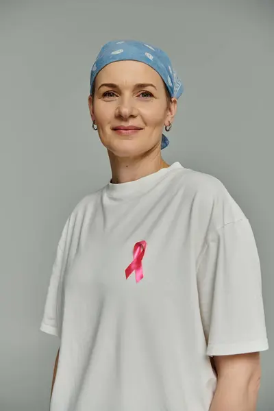 A woman with short hair wears a white shirt with a pink ribbon, symbolizing breast cancer awareness. — Stock Photo