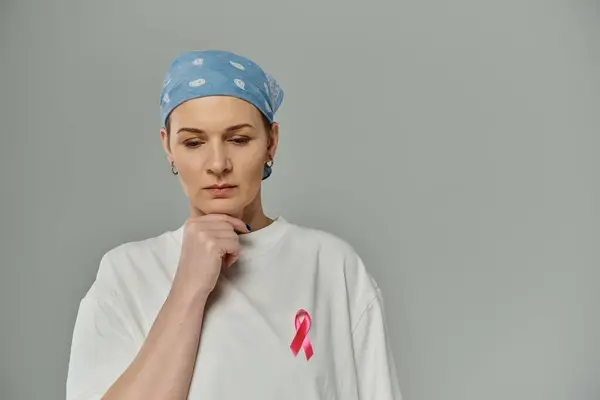 A woman with short hair wears a blue headscarf and a white shirt with a pink ribbon. — Stock Photo