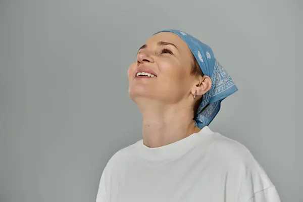 Una mujer con el pelo corto y un pañuelo azul sonríe en el techo. — Stock Photo
