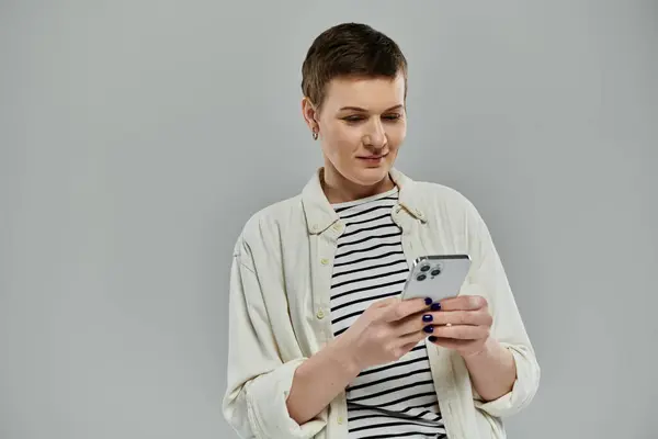A woman with short hair uses a smartphone in a casual setting. — Stock Photo