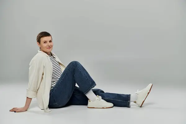 A woman with short hair sits on a studio floor, looking directly at the camera. — Stock Photo