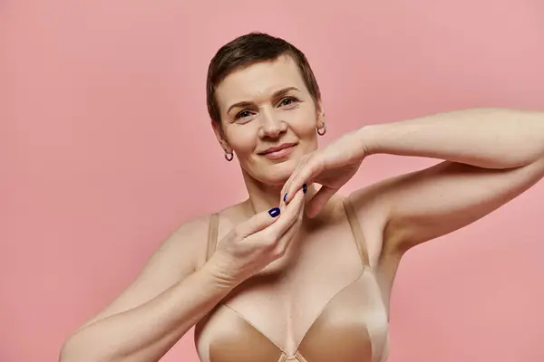 A woman with short hair in her bra looks at the camera, smiling. — Stock Photo