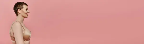 Woman with short hair in bra stands against pink backdrop, symbolizing breast cancer awareness and prevention — Stock Photo