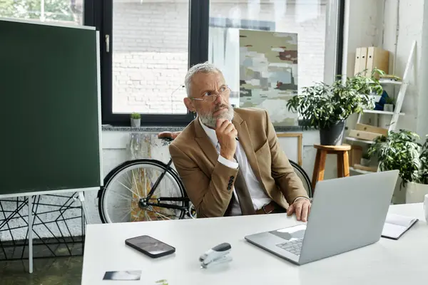 Un uomo di mezza età con la barba, indossando un abito, si siede di fronte a un computer portatile, insegnando con attenzione online, insegnante lgbtq — Foto stock