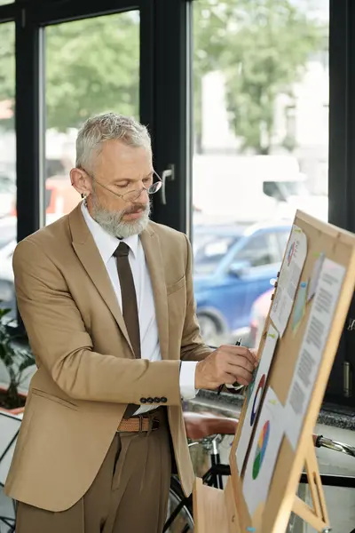 A man in a suit stands by a whiteboard, explaining charts with a pen in his hand. — Stock Photo