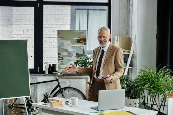 A mature, bearded man, dressed in a suit and tie, smiles as he teaches online from a laptop. — Stock Photo