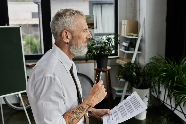 Un insegnante maturo con la barba dà una lezione online mentre si trova in una classe luminosa e moderna. — Foto stock