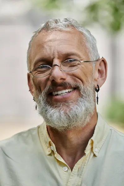 A middle-aged man with a white beard smiles warmly while standing outside a modern building. — Stock Photo