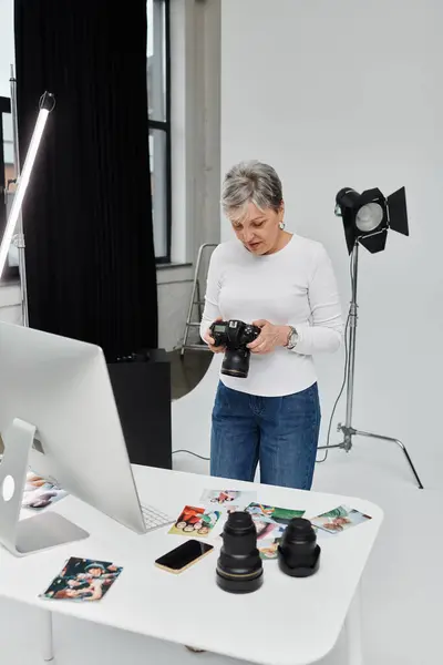A woman reviews photos on a camera in a photography studio, surrounded by equipment. — Stock Photo