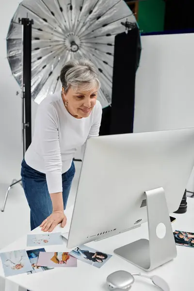 A photographer leans over a computer, reviewing images from a recent photoshoot. — Stock Photo