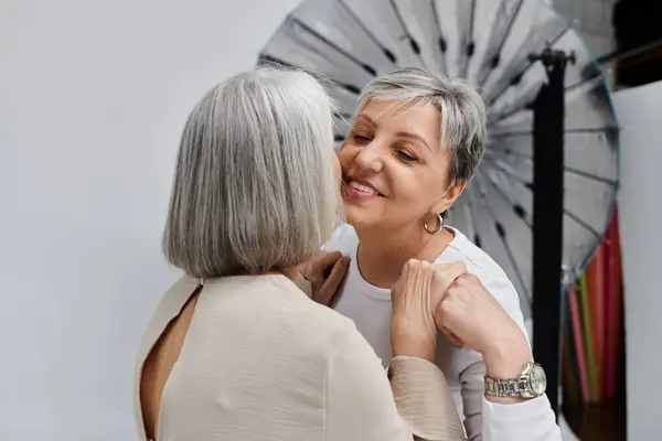 A couple shares a tender moment in a photo studio, one woman holding the other close. — Stock Photo