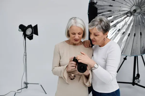 Зріла лесбійська пара позує в фотостудії, одна тримає камеру, а інші моделі для пострілу. — стокове фото