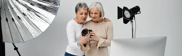 Две зрелые лесбиянки, одна фотограф, а другая модель, вместе смотрят фото в студии. — стоковое фото