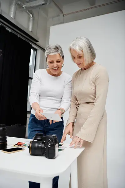 Um casal de lésbicas, um fotógrafo e outro modelo, examinam provas de uma sessão fotográfica de estúdio.. — Stock Photo