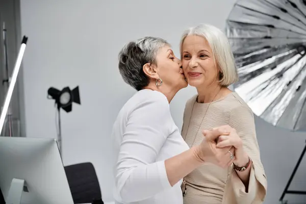 Two women, a photographer and her model, share a tender moment in a photo studio. — Stock Photo