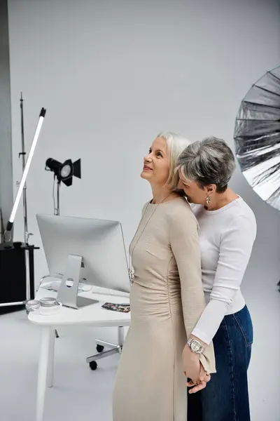 Um casal de lésbicas posa em um estúdio de fotos, uma atuando como fotógrafa, enquanto a outra é a modelo. — Stock Photo