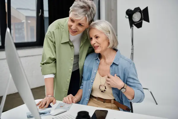 Two women, a photographer and her model, review images on a computer screen in a studio setting. — Stock Photo