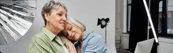 Two women embrace in a studio, one leaning her head on the other's shoulder, capturing a tender moment of affection. — Stock Photo