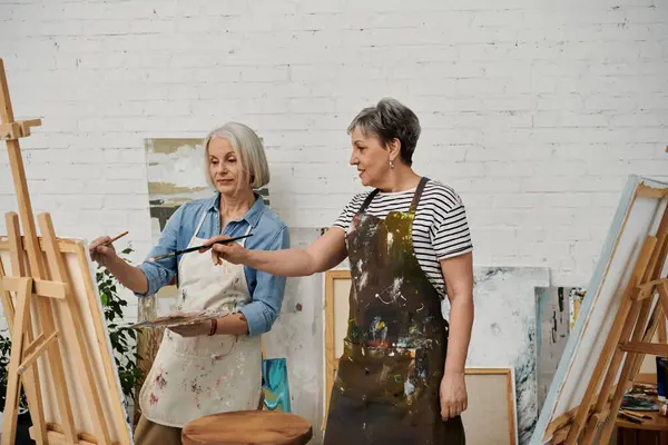A woman instructs her partner in the art of painting at their shared studio. — Stock Photo