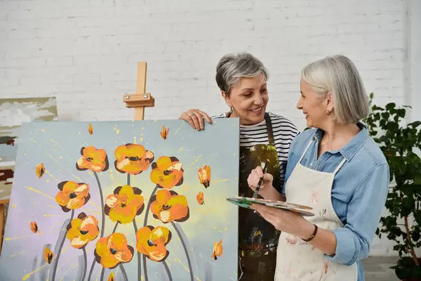 Two mature women, a lesbian couple, paint in an art studio, their smiles reflecting shared joy and creativity. — Stock Photo
