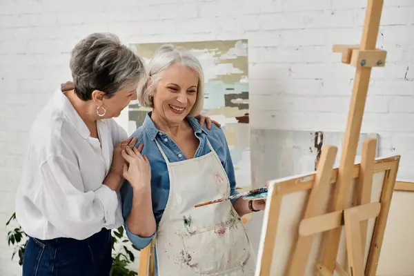 Two women, partners in life and art, share a moment of joy and creativity as they paint together in their home studio. — Stock Photo