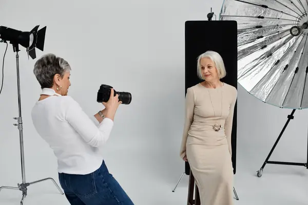 A mature lesbian couple enjoys a photo shoot in a studio, one woman taking photos of the other. — Stock Photo