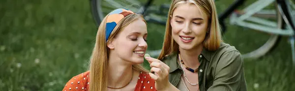 A young lesbian couple shares a snack and a laugh on a sunny day in a park. — Stock Photo
