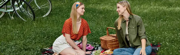 Due giovani donne condividono un picnic in un parco verde, godendosi reciprocamente compagnia. — Foto stock