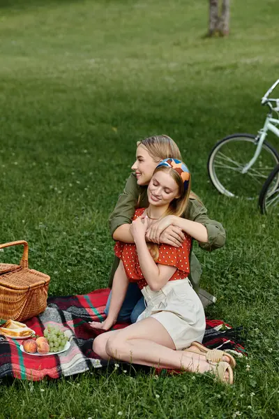 A lesbian couple shares a tender moment while enjoying a picnic in a lush green park. — Stock Photo