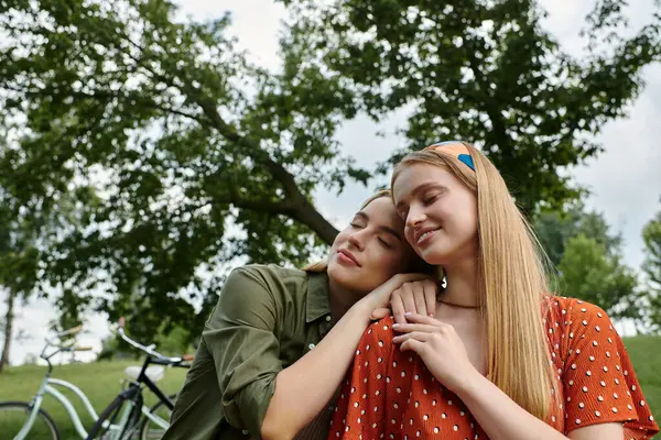 A young lesbian couple embraces in a green park, their love evident in their affectionate embrace. — Stock Photo