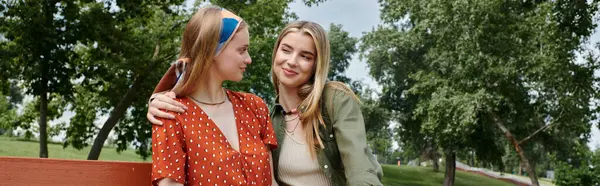 Dos mujeres jóvenes, una pareja lesbiana, disfrutan de una tarde soleada juntas en un banco del parque. — Stock Photo