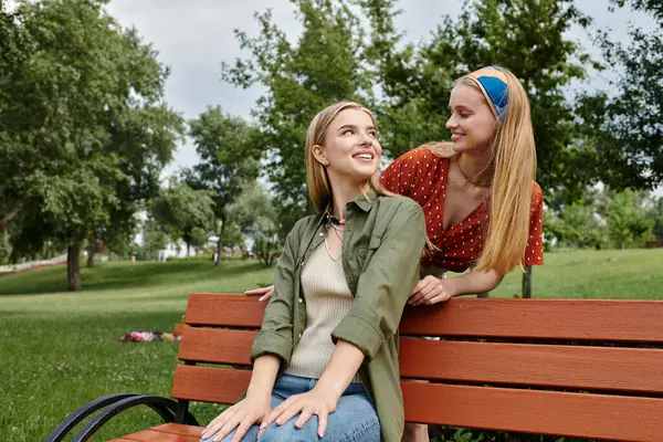 Two young women share a moment of connection on a park bench, enjoying a sunny afternoon. — Stock Photo