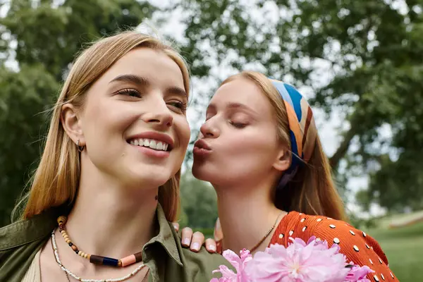 Deux jeunes femmes partagent un moment tendre, l'une embrassant la joue de l'autre tandis que l'autre sourit vivement. — Photo de stock