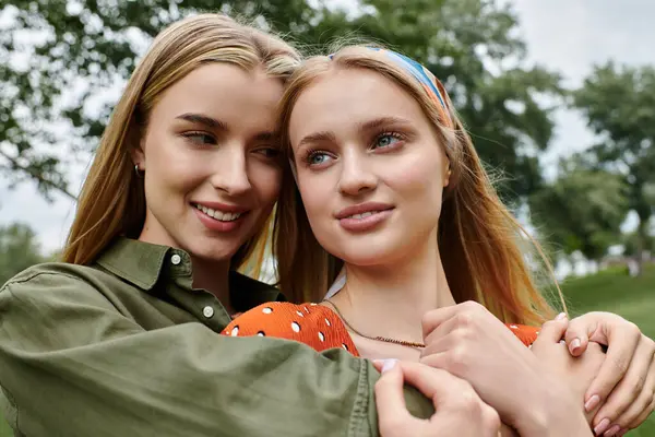 Two young women share a loving embrace in a lush green park. — Stock Photo