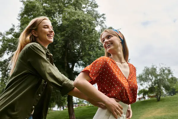 Two young women in love, laughing together on a date in a green park. — Stock Photo